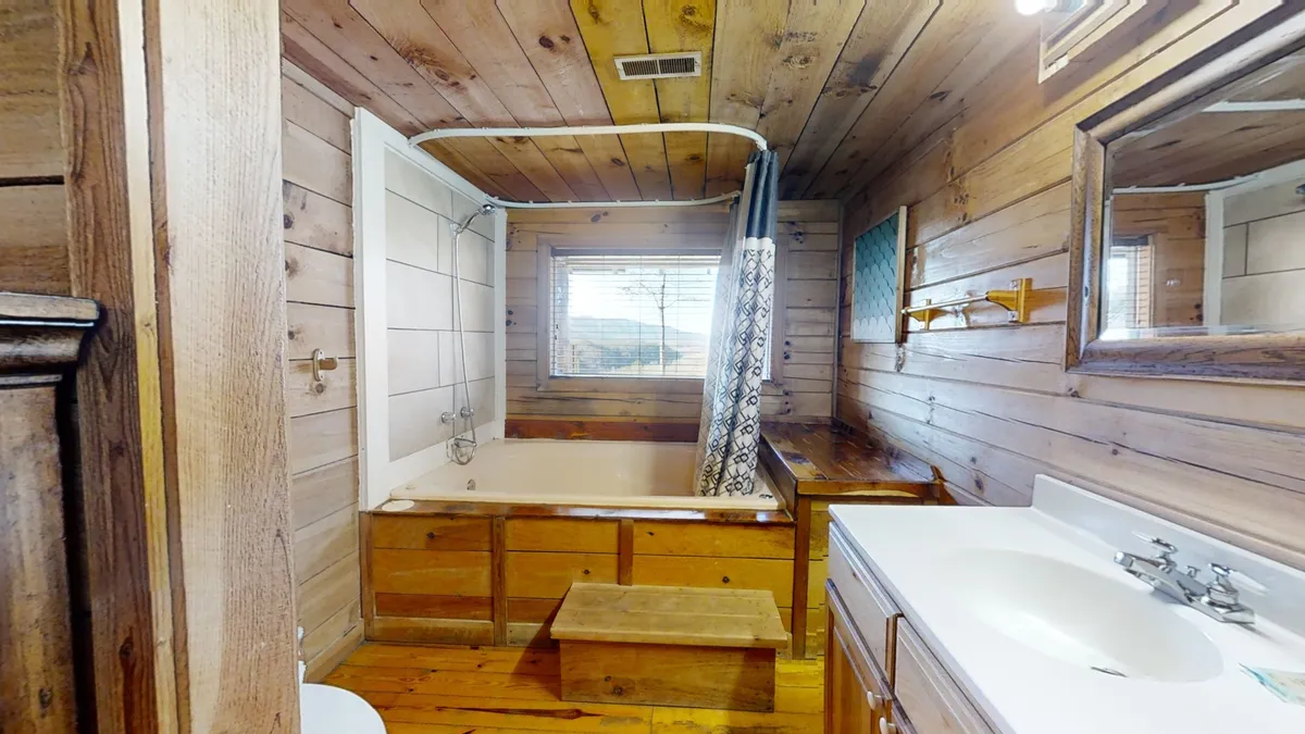 A serene bathroom scene featuring a standalone bathtub with wooden paneling, a sink, and natural light streaming through a window. The mood is peaceful, perfect for soaking and unwinding after a day of adventure.