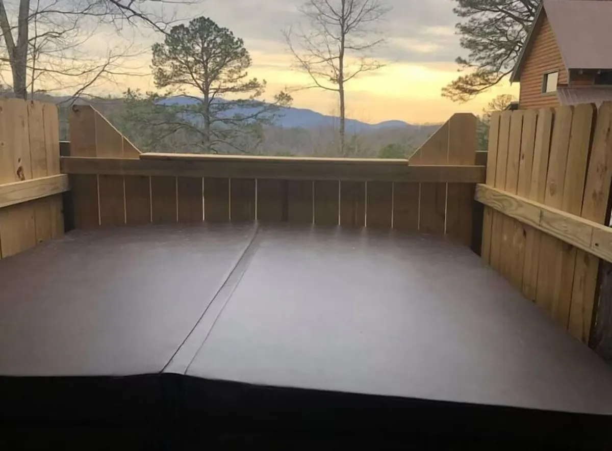 This shot emphasizes a serene mountain view framed by a rustic wooden fence at sunset, with a softly glowing sky in the background. The tranquil setting invites moments of reflection, wine under the stars, or soaking in the natural beauty with loved ones and pets.